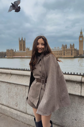 a lady wears a camel wool cloak  with black boots